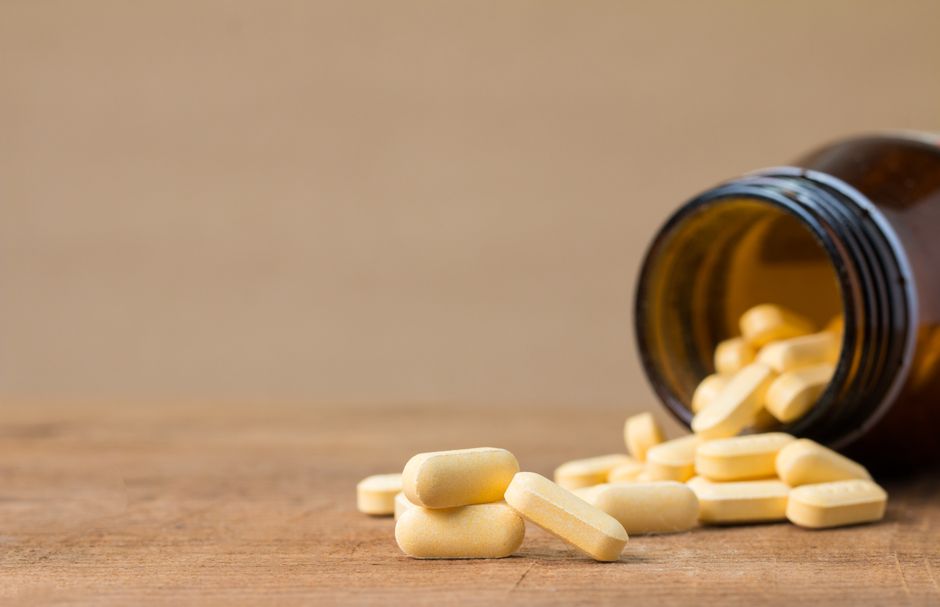 vitamin C capsules spilling on white surface close up