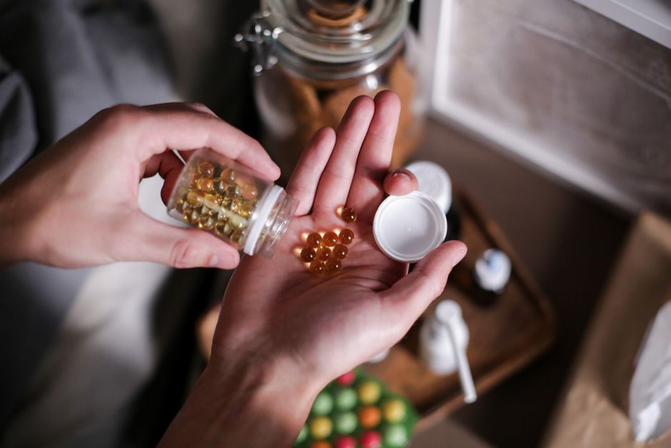stressed person exhausted holding vitamins supplement capsules on desk