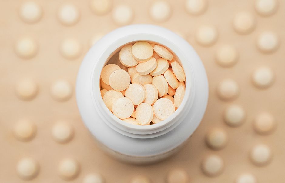vitamin C supplements capsules daily dose on wooden table natural light
